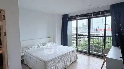 Spacious bedroom with large window offering city views and natural light.