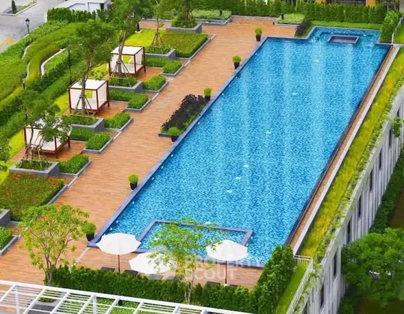 Luxurious rooftop pool with cabanas and lush greenery in modern residential complex.