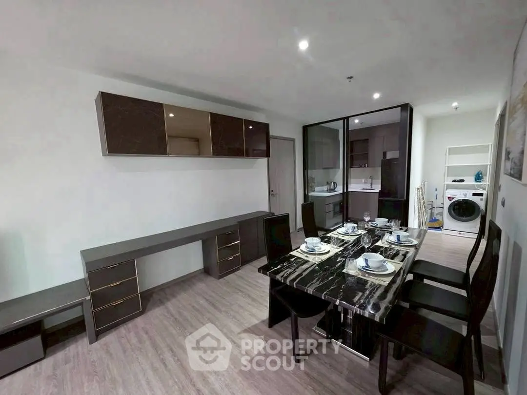 Modern dining area with sleek black table and integrated kitchen appliances.