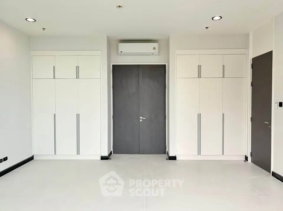 Spacious modern room with sleek built-in wardrobes and air conditioning.