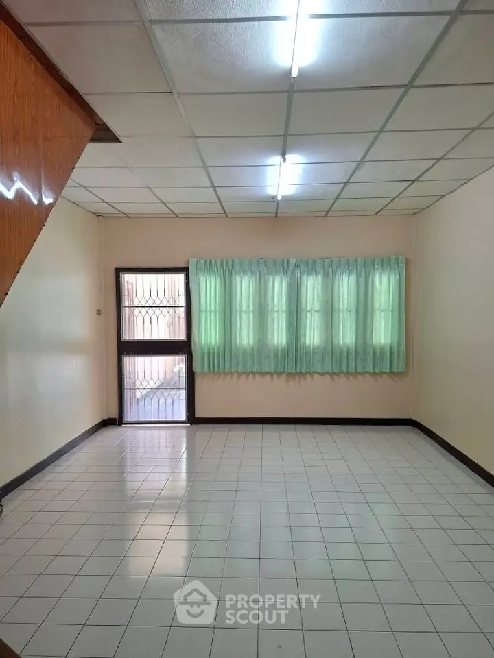 Spacious empty room with tiled floor and large windows, ideal for customization.