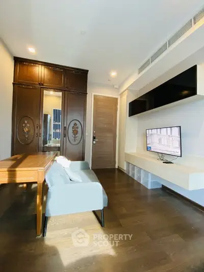Modern living room with stylish furniture and wooden flooring, featuring a mounted TV and elegant cabinetry.
