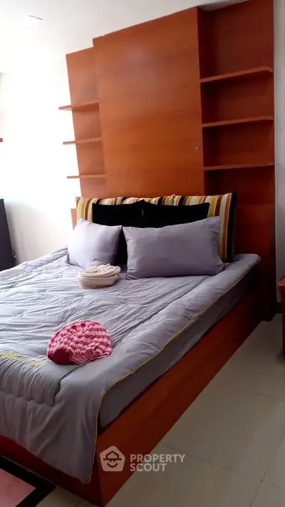 Cozy bedroom with modern wooden shelving and stylish bedding in a bright apartment.