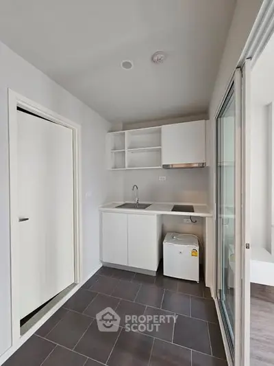 Modern compact kitchen with sleek white cabinets and built-in appliances in a minimalist apartment.