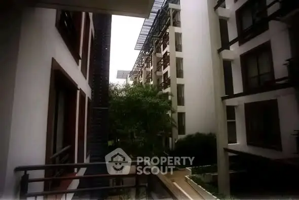 Modern apartment building exterior with lush greenery and sleek architectural design.