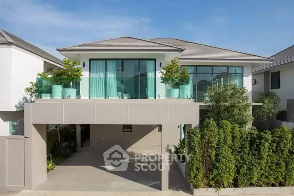 Modern two-story house with large windows and lush greenery, perfect for contemporary living.