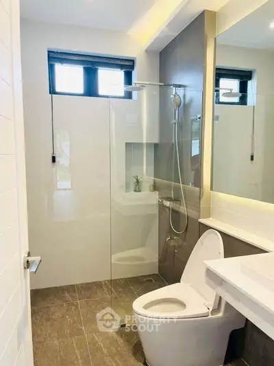 Modern bathroom with glass shower and sleek fixtures in contemporary home.