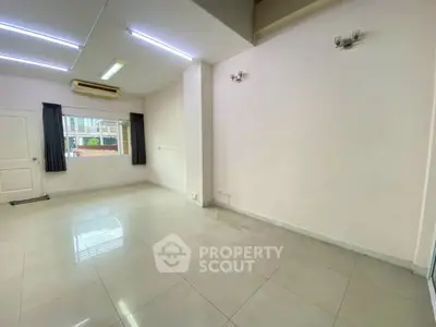 Spacious empty room with large window and tiled floor, ideal for customization.