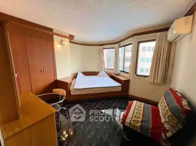 Cozy bedroom with built-in wardrobe and large windows offering city views.