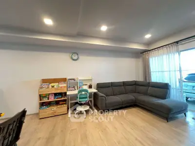 Spacious living room with modern gray sectional sofa and children's play area, perfect for family gatherings.