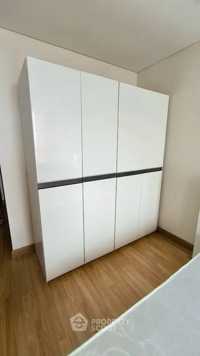 Modern bedroom with sleek white wardrobe and wooden flooring