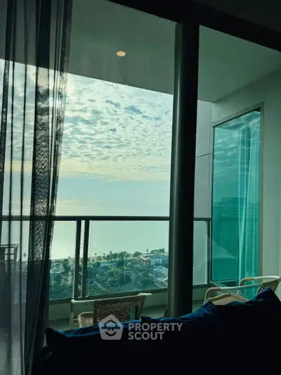 Stunning high-rise balcony view with ocean and cityscape, perfect for relaxation and enjoying sunsets.