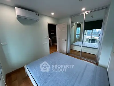 Modern bedroom with mirrored closet and city view, featuring sleek air conditioning unit.