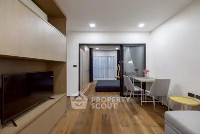 Modern living room with wooden flooring and sleek furniture, featuring a TV and dining area.