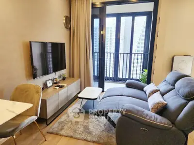 Modern living room with balcony view, featuring cozy seating and sleek entertainment setup.