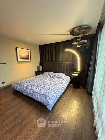 Modern bedroom with stylish lighting and wooden flooring, featuring a cozy bed and elegant decor.