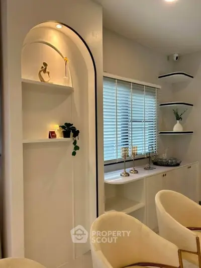 Elegant modern living room with stylish decor and natural light, featuring cozy seating and decorative shelves.