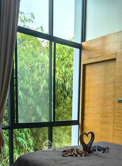 Luxurious bedroom with large windows and lush greenery view, perfect for nature lovers.