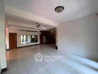 Spacious living room with tiled flooring and staircase, ideal for modern family living.