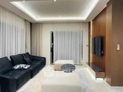 Modern living room with sleek black sofa, elegant lighting, and stylish decor.