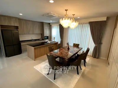 Luxurious open-layout kitchen and dining area with elegant chandelier and modern appliances.