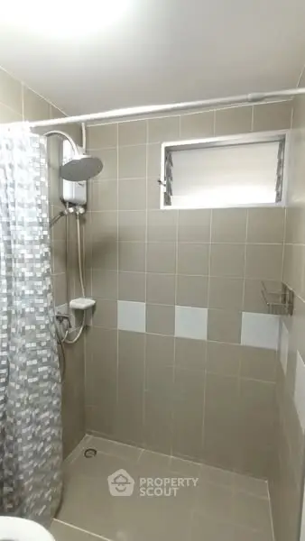 Modern bathroom with tiled shower area and window for ventilation.
