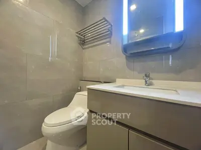 Modern bathroom with sleek fixtures and illuminated mirror in a contemporary apartment.