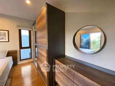 Modern bedroom with stylish wooden furniture and large windows offering natural light.