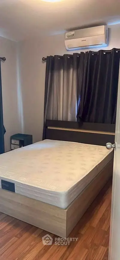 Cozy bedroom with air conditioning and wooden flooring, perfect for restful nights.