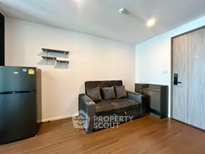 Modern living room with sleek sofa and compact fridge in stylish apartment.