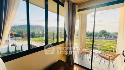 Stunning balcony view with expansive windows overlooking lush greenery and hills.