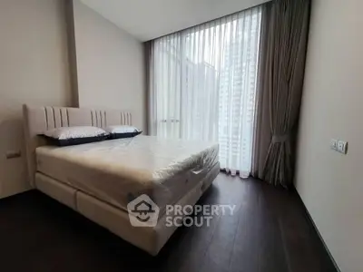 Modern bedroom with large windows and city view, featuring a comfortable bed and elegant curtains.