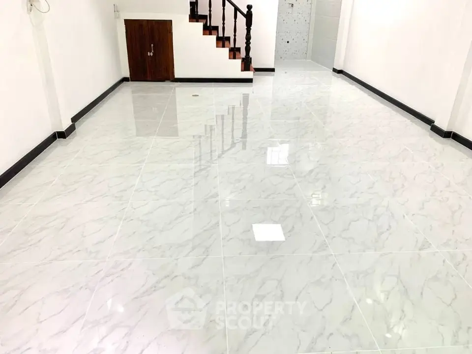Spacious interior with glossy marble flooring and wooden staircase, ideal for modern living.