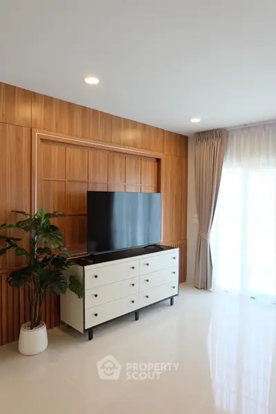 Modern living room with sleek TV unit and large window for natural light.