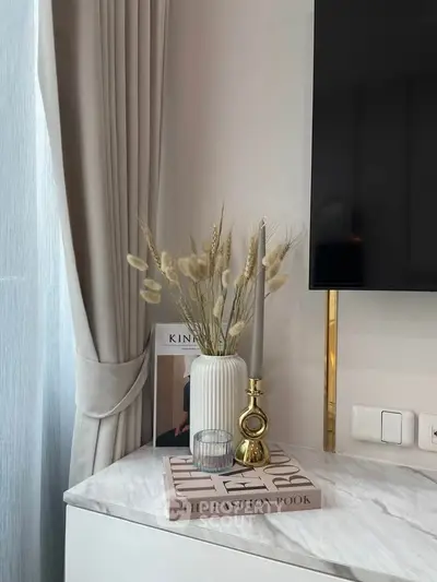 Elegant interior decor with marble top, vase, and candle holder beside a TV.