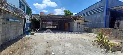 Spacious industrial lot with covered area and potential for development under clear blue skies.