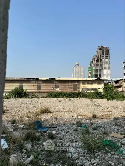 Vacant urban lot with potential for development, surrounded by cityscape and high-rise buildings.