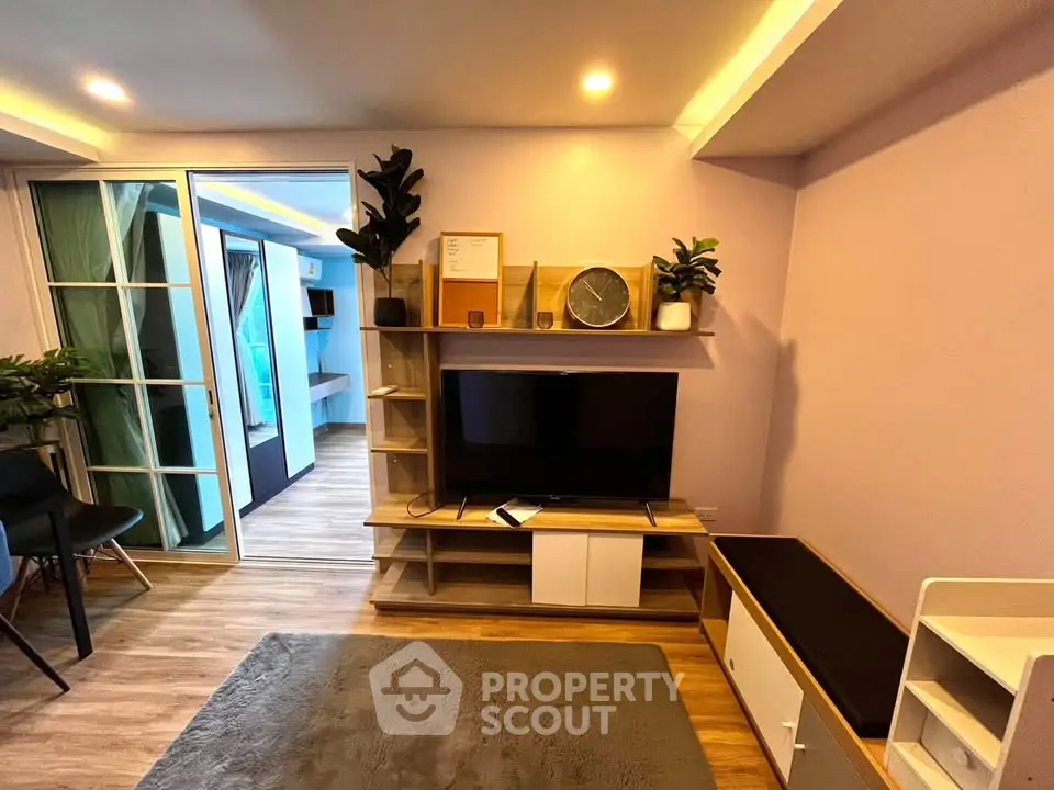 Modern living room with stylish decor and open layout, featuring a TV and elegant shelving.