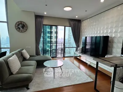 Modern living room with large TV, stylish sofa, and city view balcony.