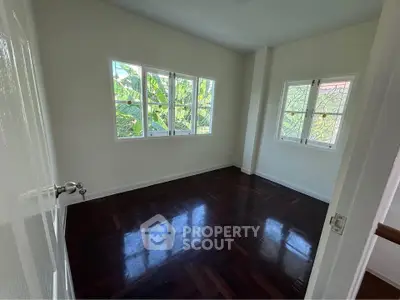 Spacious bedroom with hardwood floors and large windows offering natural light.