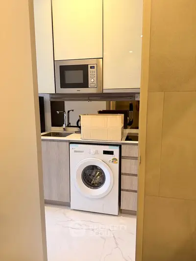 Compact modern kitchen with built-in microwave and washing machine, ideal for urban living.