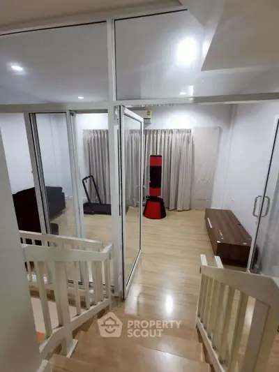 Modern home interior with glass doors and wooden flooring, featuring a cozy living area and exercise equipment.