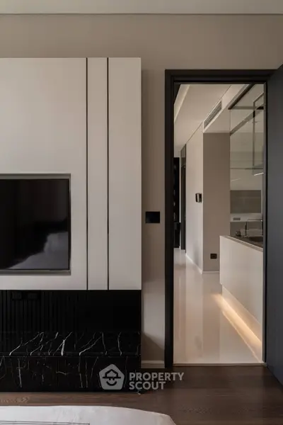Modern interior with sleek TV setup and view into contemporary kitchen