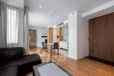 Modern open-plan living room with sleek kitchen and dining area, featuring wooden floors and contemporary furniture.