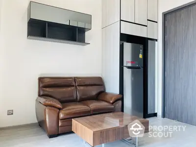 Modern living room with sleek leather sofa, wooden coffee table, and a stylish floating shelf, complemented by a contemporary refrigerator.