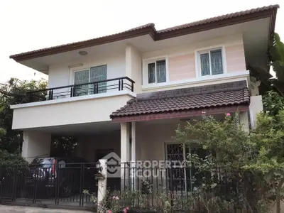 Charming two-story house with balcony and lush garden in serene neighborhood.