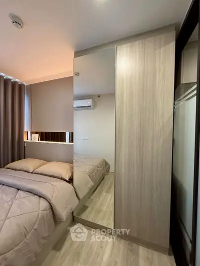 Modern bedroom with mirrored wardrobe and cozy bedding in stylish apartment.