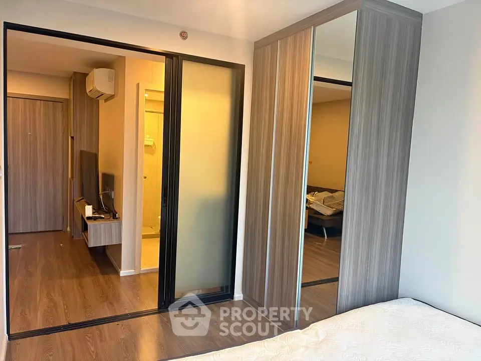 Modern bedroom with sliding wardrobe doors and wooden flooring in a stylish apartment.