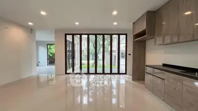 Spacious modern living room with large glass doors and sleek kitchen cabinetry.