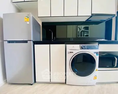 Modern kitchen with sleek appliances including fridge and washing machine.